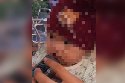 Tangkap layar video tular menunjukkan seorang lelaki meletakkan ‘pod’ vape ke mulut seorang bayi.