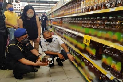 Saifullizan (kanan) meninjau harga minyak masak botol yang dijual di sebuah pasar raya, di sini ketika Walkabout Pemantauan Pelaksanaan Penentuan Harga Runcit Maksimum Bagi Minyak Kelapa Sawit Tulen Kemasan Botol Negeri Perak pada Selasa.