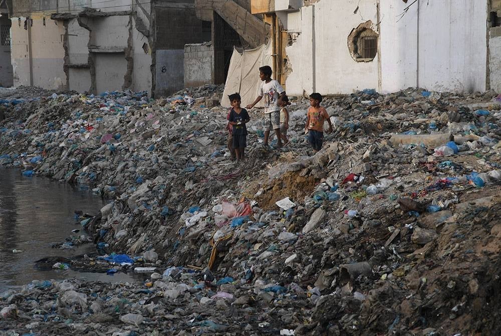 Kanak-kanak bermain di kawasan penempatan yang dipenuhi sampah sarap di Karachi.