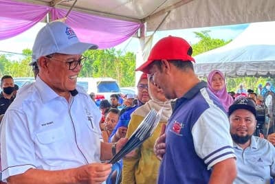 Wan Rosdy (kiri) menyerahkan surat tawaran STW kepada peserta terpilih ketika majlis itu di Kampung Kuala Medang, Kuala Lipis pada Sabtu.