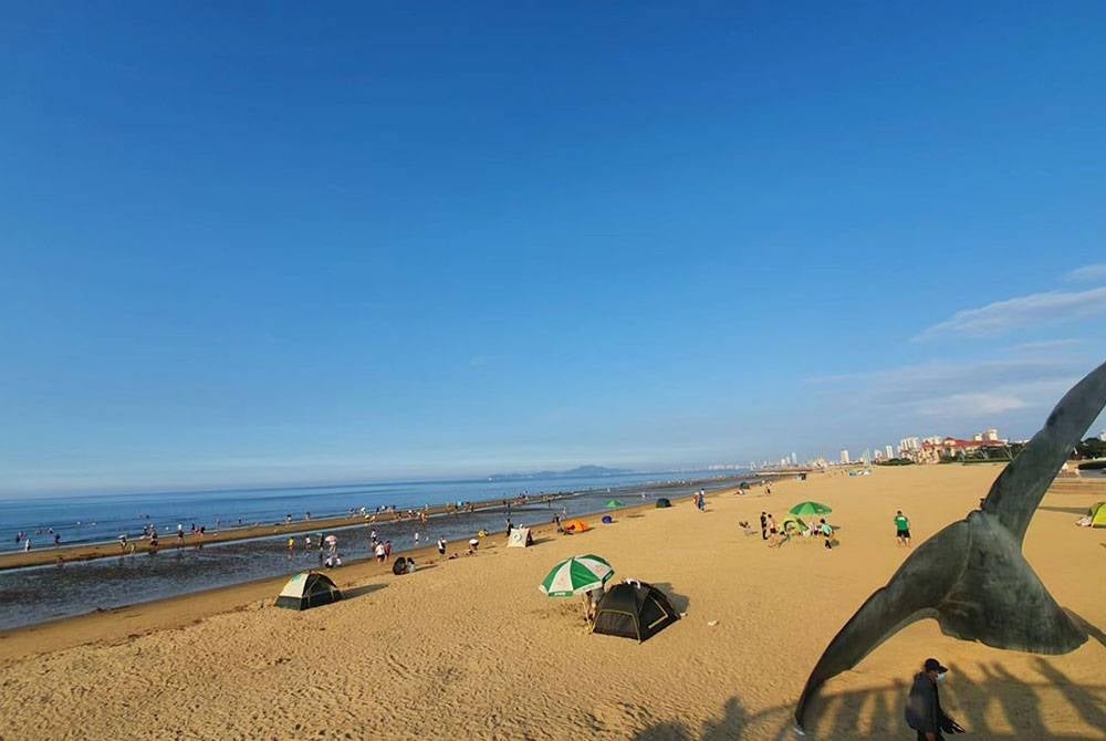 Orang ramai bermandi-manda di tepi pantai pada musim panas.