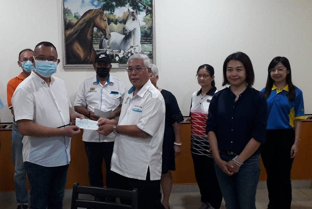 Hassan (kanan) menyerahkan cek sumbangan kepada pihak pengurusan SJKC Nam Heng pada Isnin.