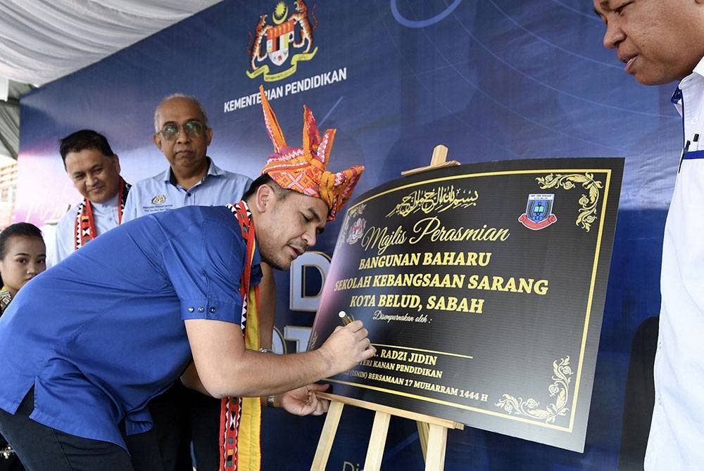 Menteri Kanan Pendidikan Datuk Dr Radzi Jidin menurunkan tandatangan sebagai simbolik perasmian bangunan baharu Sekolah Kebangsaan (SK) Ulu Kukut dan SK Sarang hari ini. - Foto Bernama