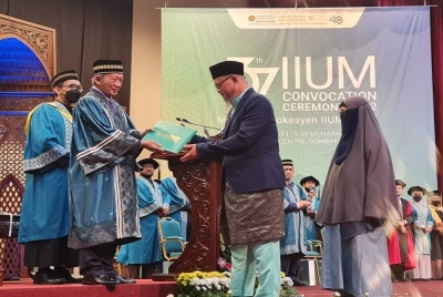 Samsudin (kiri) menyampaikan ijazah kepada Ahmad Sabari yang mewakili anaknya, Allahyarhamah Siti Hafsah pada majlis konvokesyen UIAM Kampus Gombak pada Isnin.