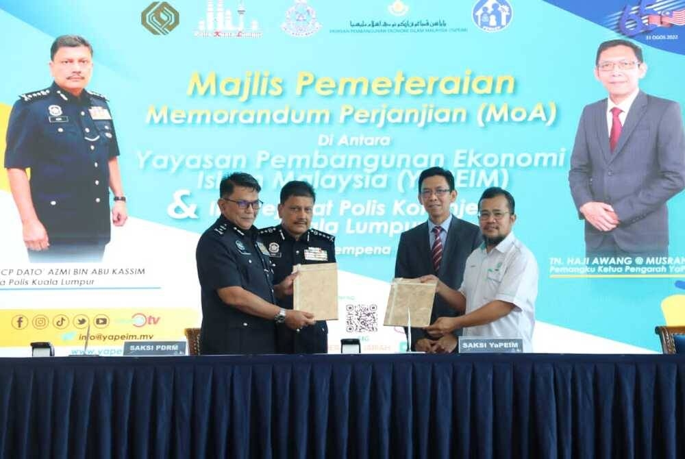 Awang (dua dari kanan) dan Azmi (dua dari kiri) menyaksikan meterai MoA yang ditandatangani oleh dua pihak pada program Sehari Bersama YaPEIM di IPK Kuala Lumpur pada Selasa.