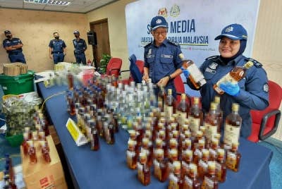 Zazuli (dua dari kanan) bersama pegawainya menunjukkan botol berisi arak yang dirampas JKDM Zon Tengah Unit III (LTAKL) di Kompleks Kastam KLIA pada sidang media kejayaan melumpuhkan sindiket pengilangan minuman keras tidak berlesen di Lembah Klang hari ini. - Foto Bernama