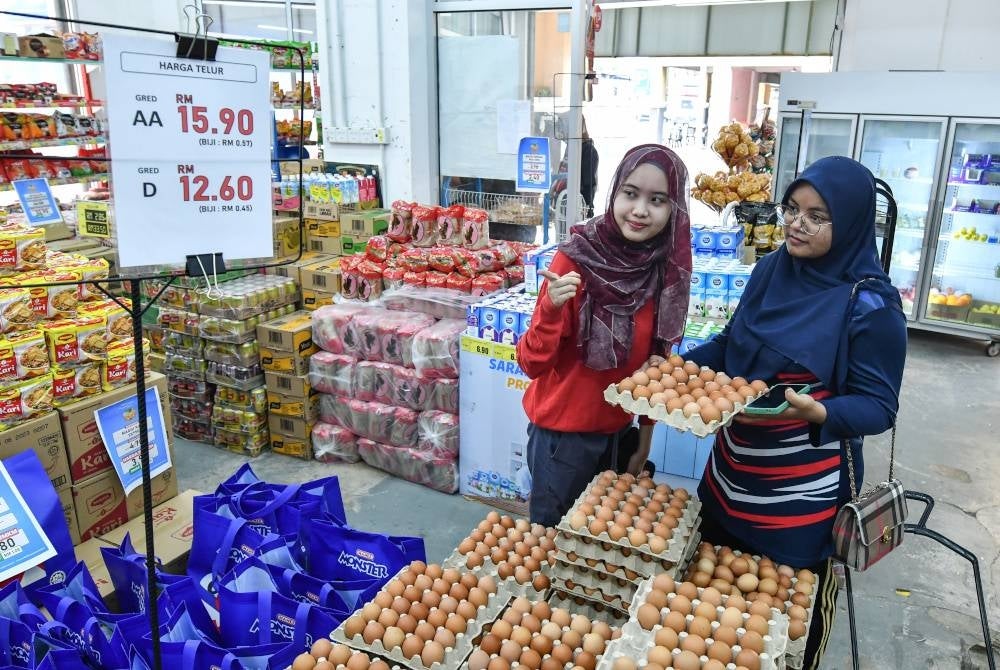 Nurul Atikah Mohd Asri, 22, (kiri) dan rakannya Rabiatul Adawiyah Jamil Jaifiri, 22, mendapatkan barangan keperluan harian pada harga murah menerusi Program Jualan Murah Keluarga Malaysia (PJMKM) di Pasar Mini 9 Mart, Kampung Ladang Tok Pelam hari ini.  Jualan tersebut dapat membantu mengurangkan beban rakyat berpendapatan B40.  