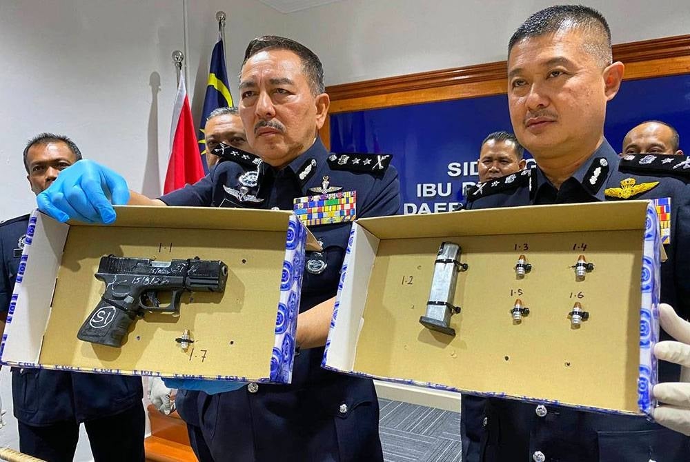 Muhamad Zaki (kiri) menunjukkan sepucuk pistol jenis Glock 19 Austria warna hitam dan peluru di dalam 'chamber' serta empat butir peluru hidup yang dirampas.