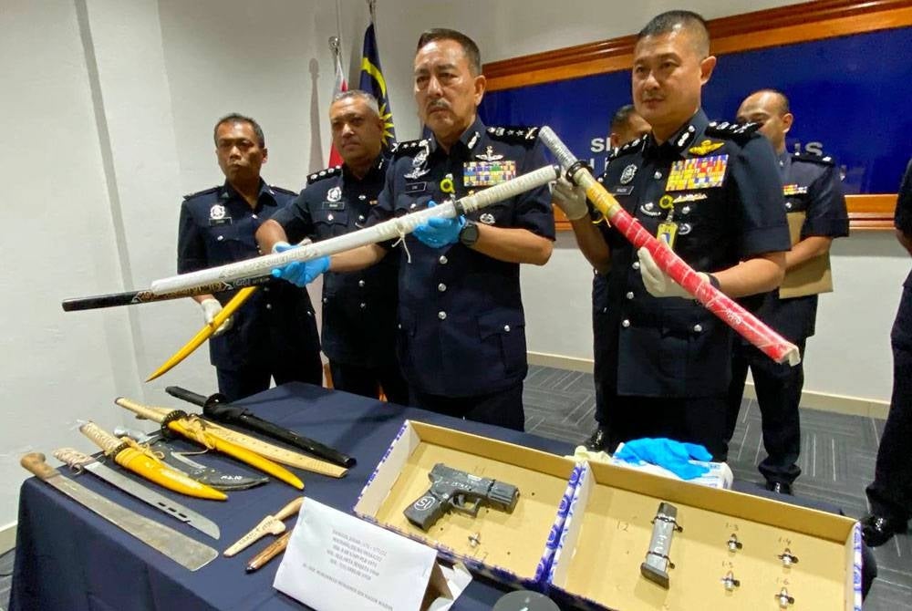 Muhamad Zaki (dua dari kanan) menunjukkan sebahagian daripada senjata tajam yang dirampas daripada seorang lelaki di Kampung Air Belaga, Ulu Sat, Machang pada Isnin lalu.