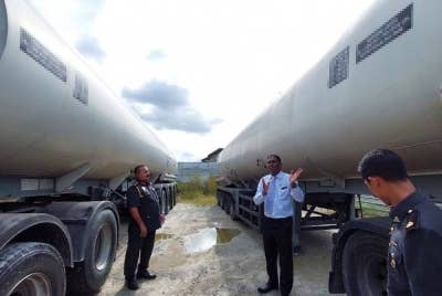 Jegan (dua,kanan) menunjukkan lori tangki yang ditemui dalam premis yang diserbu pada Isnin.