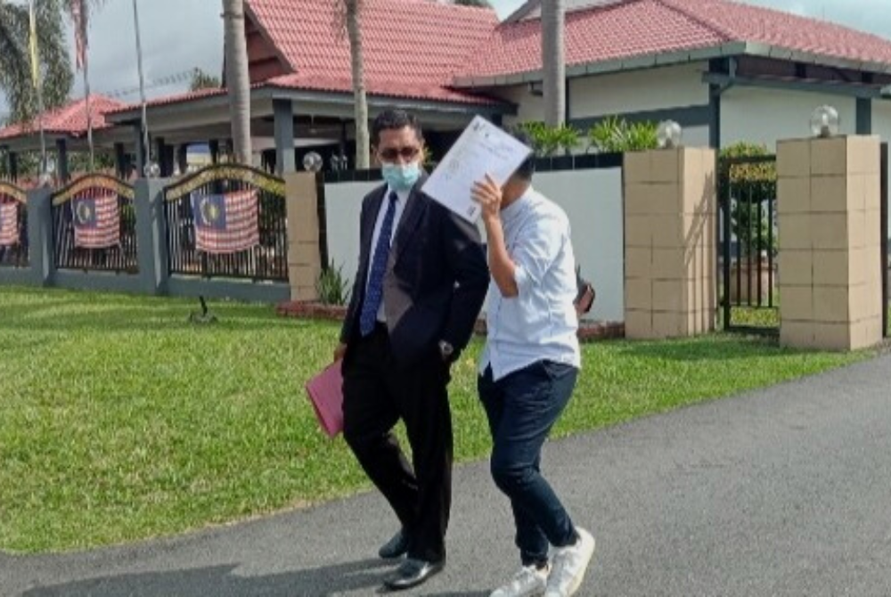 Tertuduh (kanan) dilihat keluar dari perkarangan mahkamah bersama peguamnya setelah selesai membayar denda.