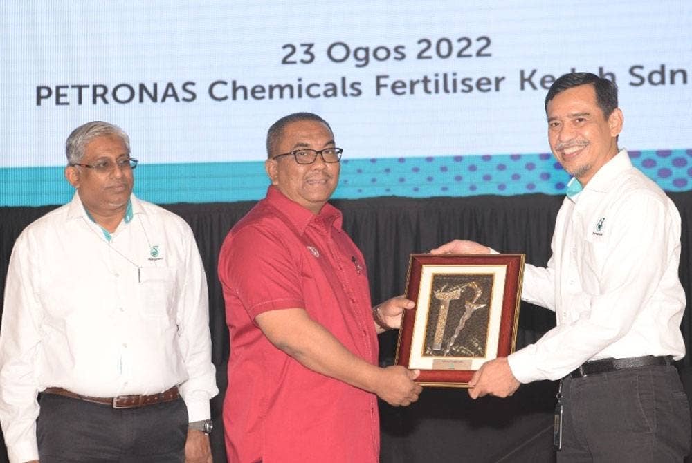 Mohd Yusri (kanan) menyampaikan cenderahati kepada Muhammad Sanusi ketika melancarkan projek loji melamina di Kompleks Petronas Chemical Fertiliser Kedah Sdn Bhd di Gurun pada Selasa.