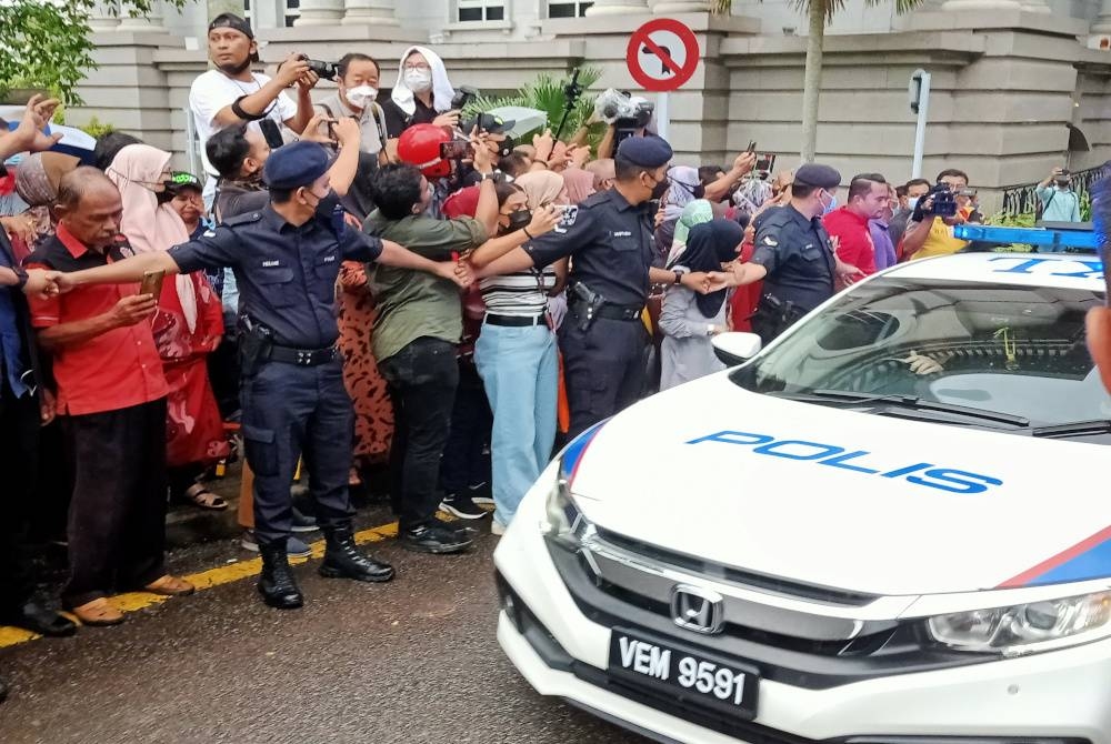 Penyokong Najib memberikan sokongan kepada bekas Perdana Menteri itu sambil dikawal anggota polis.