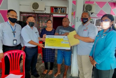 Zainol (dua dari kiri) menyerahkan faedah pengurusan mayat kepada waris mendiang, E Darwin Liew di kediamannya di Taman Padu di sini pada Selasa.