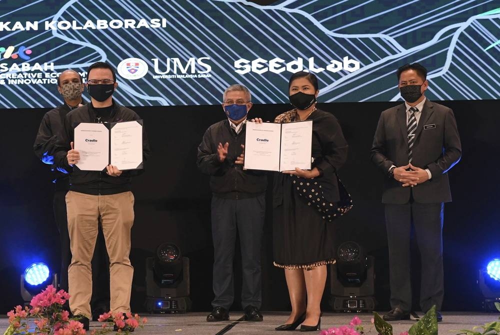 Dr Adham Baba (tiga dari kanan) menyaksikan pertukaran dokumen Memorandum Persefahaman (MoU) antara Pemangku Ketua Pegawai Eksekutif Kumpulan Cradle, Norman Matthieu Vanhaecke (kiri) dengan Pengurus Besar SECNIC Viviantie Sarjuni (dua dari kanan) pada majlis pelancaran MyStartup East Malaysia Region Roadshow Sabah di Pusat Konvensyen Antarabangsa Sabah pada Rabu. - Foto Bernama