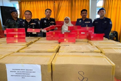 Amran (tiga dari kiri) menunjukkan rokok seludup yang dirampas di tepi sungai Pasir Pekan Hilir, Tumpat pada Rabu semasa Op Bersepadu.