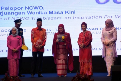 Tunku Azizah Aminah Maimunah Iskandariah (tengah) berkenan menunjukkan buku “Keberanian Pelopor NCWO, Inspirasi Perjuangan Wanita Masa Kini” selepas melancarkannya pada Majlis Sambutan Hari Wanita Kebangsaan ke-60 di Dewan Perdana Felda, pada Khamis. - Foto Bernama