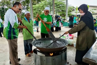 Mohd Hayati (dua dari kanan) sedang mengacau bubur asyura pada Program Asyura Perdana Pas Kawasan Pendang di sini pada Khamis.