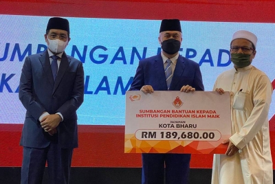 Tengku Mohamad Rizam (tengah) menyampaikan sumbangan zakat kepada salah seorang penerima pada Laporan Khas Terimaan dan Perbelanjaan MAIK bagi Januari hingga Jun Tahun 2022 di Hotel Perdana, Kota Bharu pada Khamis.