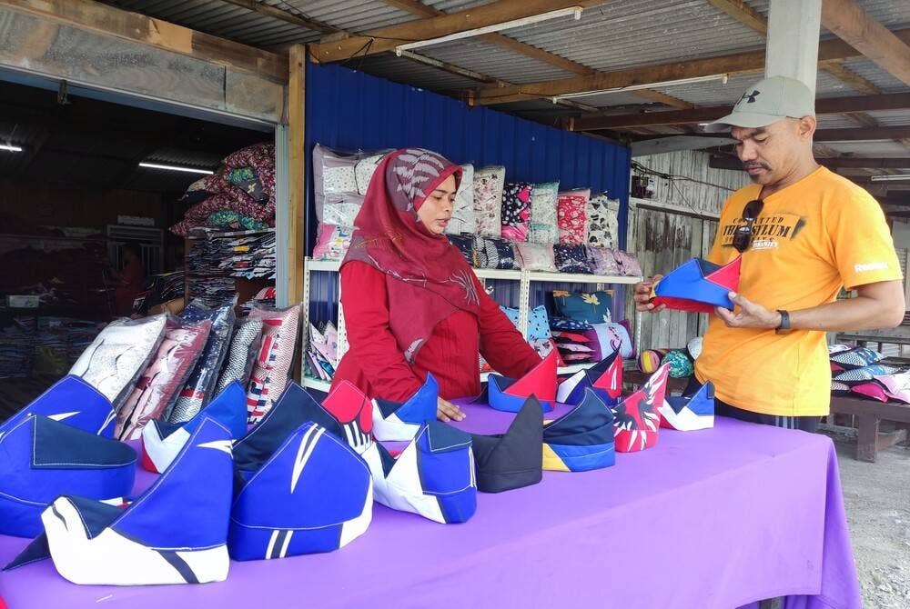 Norwilia (kiri) melayan pelanggan yang datang membeli tanjak di kedainya.