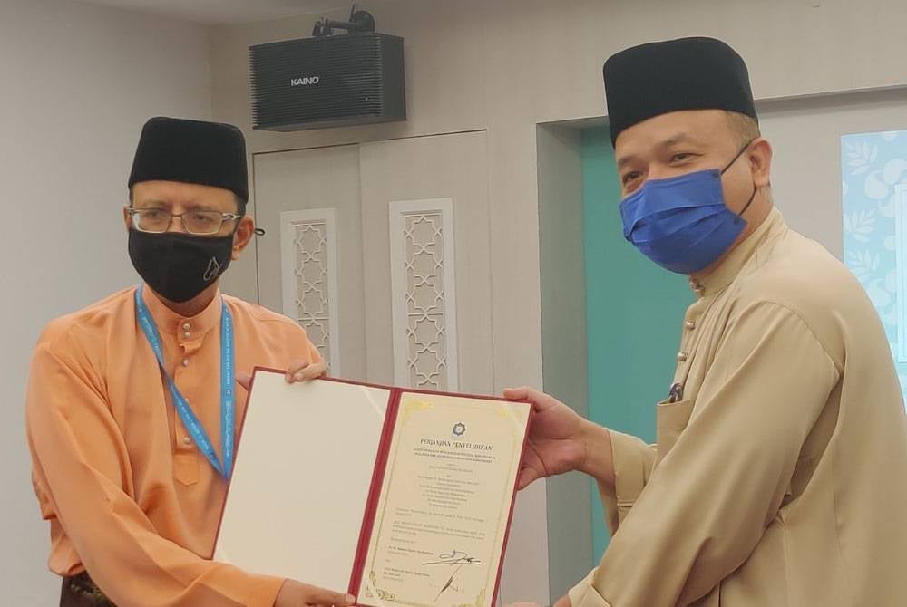 Ahmad Shahir (kiri) menyerahkan perjanjian kepada salah seorang penyelidik pada Majlis Penyerahan Perjanjian Penyelidikan Tahun 2022 dan Serahan Laporan Hasil Penyelidikan Tahun 2021 di Dewan Anggerik, Hotel De Palma, Seksyen 19 di Shah Alam pada Jumaat.