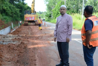 Salim (kiri) meninjau kerja-kerja pembinaan parit konkrit di kawasan Machang Kudung.