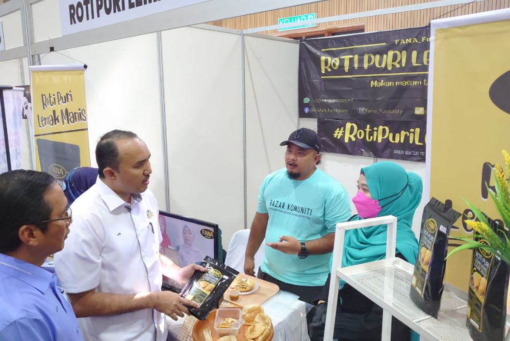 Mohd Jafni (dua dari kanan) menyantuni seorang peserta Program Bazar Komuniti Iskandar Puteri di Taman Nusantara, Iskandar Puteri pada Sabtu.