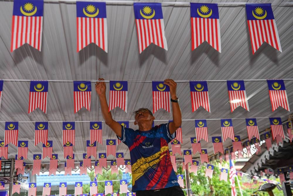Jaafar melakukan kerja-kerja menghias halaman rumah dengan memasang pelbagai saiz Jalur Gemilang di rumahnya di Taman Kerian baru-baru ini. - Foto Bernama