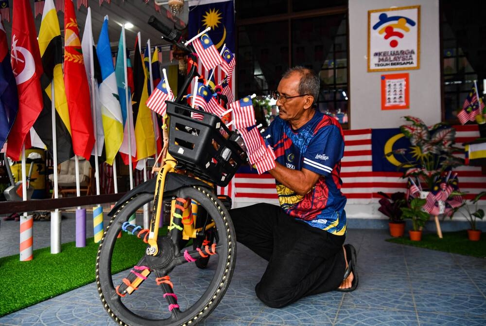 Jaafar menghias basikalnya dengan Jalur Gemilang menjelang sambutan hari kebangsaan. - Foto Bernama