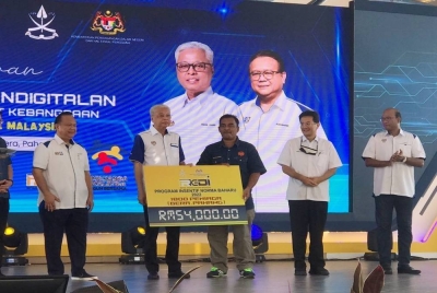 Ismail Sabri menyerahkan replika cek kepada peniaga pada Majlis Pelancaran Program Inisiatif Pendigitalan Sektor Peruncitan ReDI dan Penjenamaan Semula Program JMKM peringkat kebangsaan di Dataran Kerayong pada Sabtu.