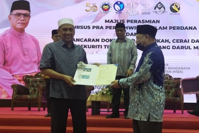 Syed Ibrahim (kiri) menerima contoh kad perakuan nikah bersekuriti tinggi disampaikan Dr Zulkifle pada Majlis Perasmian Kursus Pra Perkahwinan Islam Perdana dan Pelancaran Dokumen Rasmi Nikah, Cerai dan Rujuk Bersekuriti Tinggi Negeri Pahang di Dewan Kompleks MBK pada Sabtu.