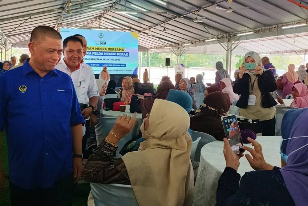 Saarani menyantuni warga Felda Perak yang hadir pada Program Mesra Bersama Peneroka Felda di Laman Seri Ridzuan di sini pada Ahad.