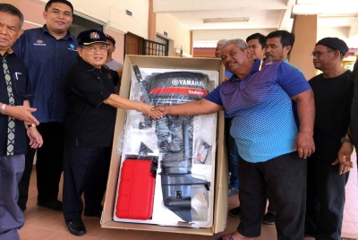 Ahmad (tiga dari kiri) menyerahkan bantuan enjin sangkut bernilai RM10,000 kepada salah seorang nelayan di Jeti Nelayan Kuala Sebatu, pada Ahad. - Foto Bernama