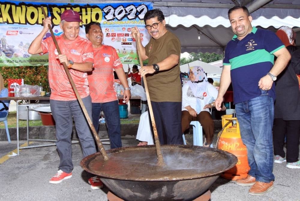 Muhammad Nasir (kiri) dan Md Alwi (tengah) mengacau bubur asyura ketika program yang berlangsung di pekarangan Kompleks Karangkraf pada Ahad.