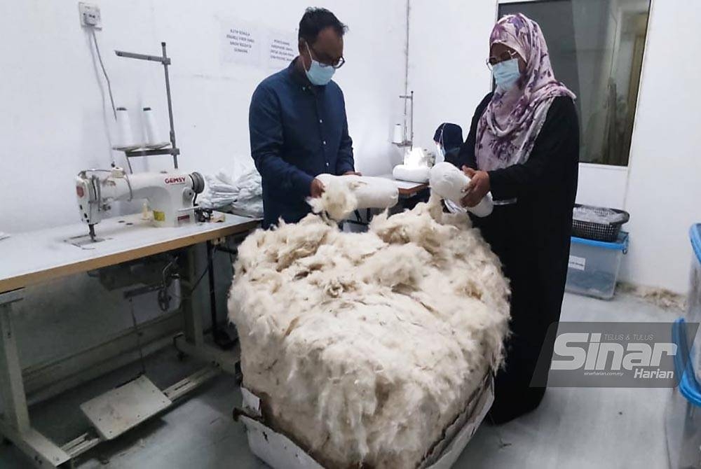 Suriya (kanan) dan Mohd Badrul melihat kekabu yang akan digunakan untuk menyiapkan pelbagai produk mereka di Taman Senangin, Alor Setar.