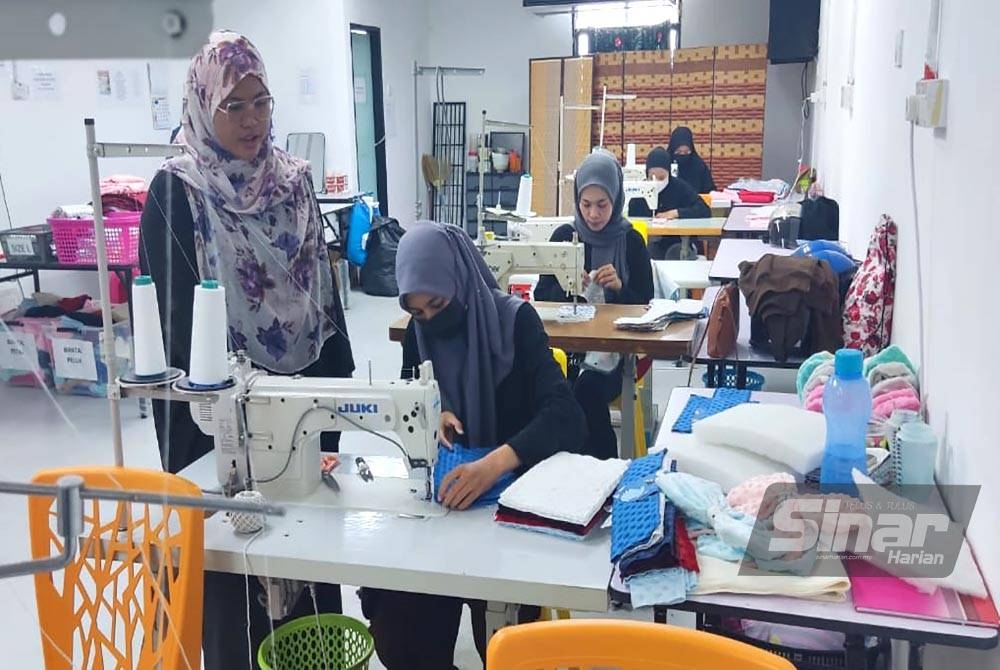 Suriya (kiri) sentiasa memeriksa kualiti jahitan agar produk yang dihasilkan memuaskan hati pelanggan.