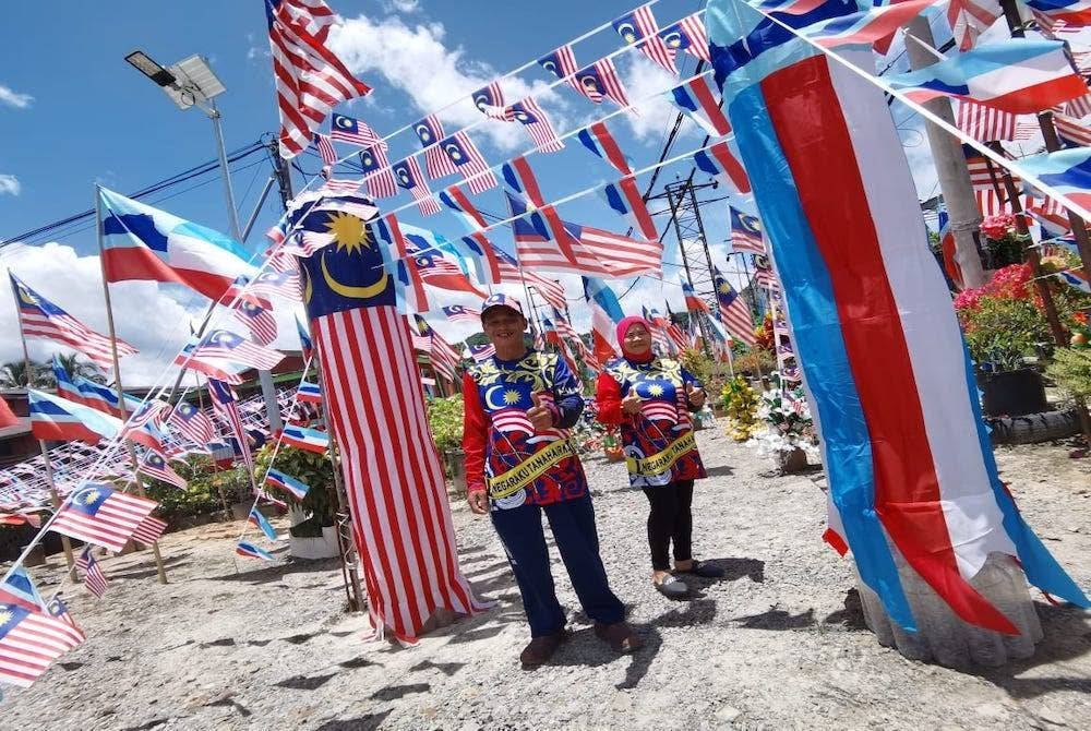 Mohd Arif bersama isterinya, Linah berada di halaman rumah mereka dengan berlatarbelakangkan hiasan bendera Jalur Gemilang dan Sabah di Kampung Melati, Beaufort.