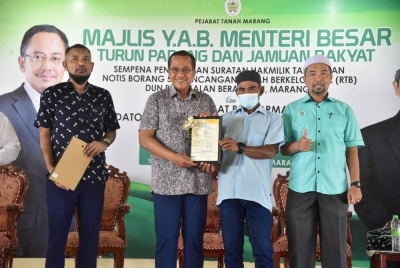 Ahmad Samsuri (dua dari kiri) ketika hadir pada Majlis Turun Padang dan Jamuan Rakyat sempena Penyerahan Suratan Hakmilik Tanah dan Notis Borang 5A RTB DUN Pengkalan Berangan di Dewan Sivik Merchang, Marang pada Isnin.