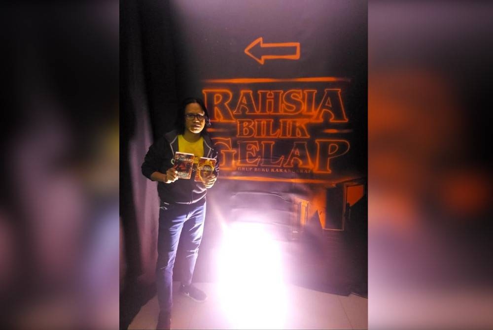 Muhammad Khair di hadapan pintu masuk Rahsia Bilik Gelap yang mengisi slot Jualan Gudang Karangkraf 2022.