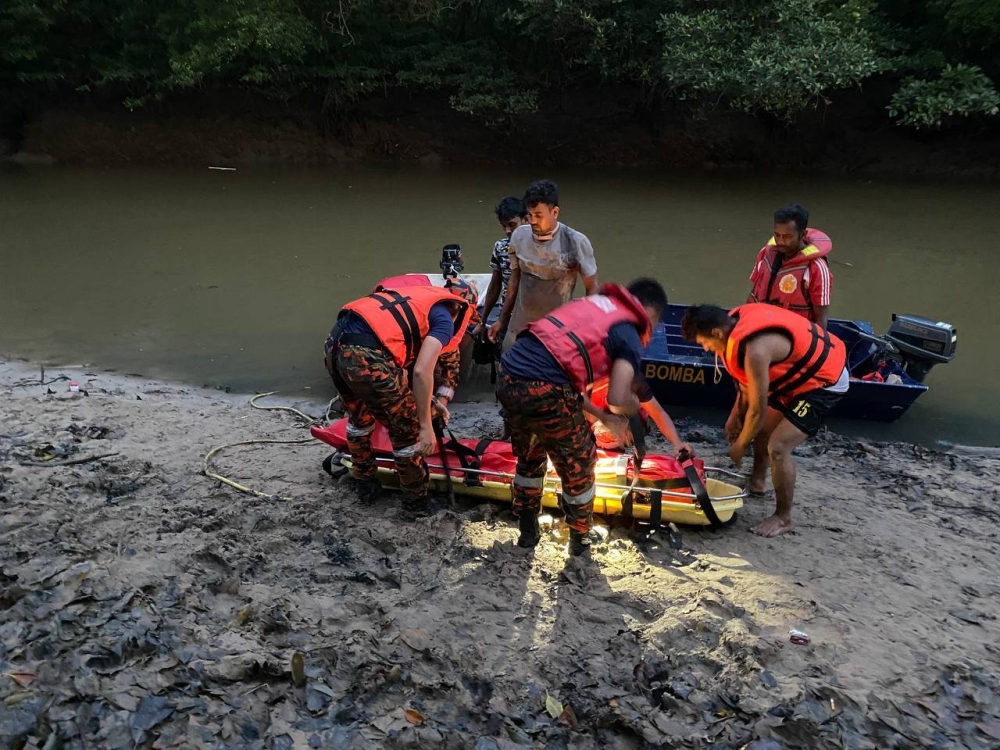 Anggota bomba mengangkat mayat mangsa yang hanyut semasa menyeberang sungai.