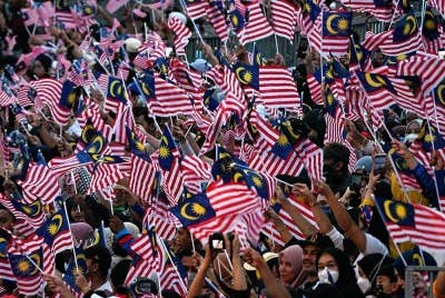 Orang ramai yang hadir mengibarkan Jalur Gemilang bagi menyaksikan acara perbarisan dan perarakan sambutan Hari Kebangsaan 2022 di Dataran Merdeka pagi Rabu. - Foto Bernama