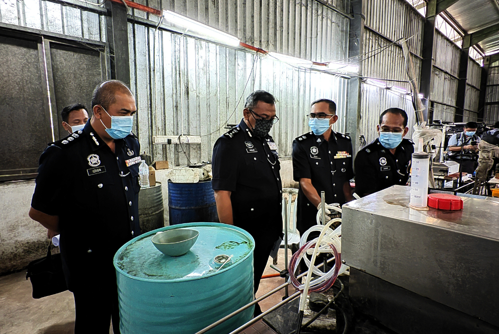 Ruslan (dua dari kiri) melihat mesin memproses arak di kilang yang diserbu.