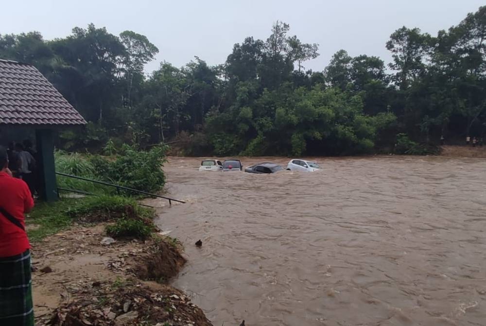 Pengunjung melihat kenderaan yang dihanyutkan kepala air dalam kejadian di Lata Payung, Ulu Kasar di Setiu pada petang Jumaat. - Foto Ihsan pembaca