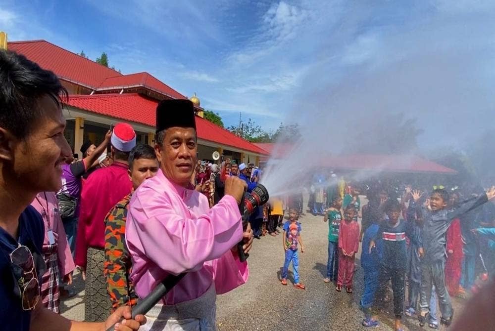 Dr Zaini (dua dari kiri) menyembur air kepada kanak-kanak yang akan dikhatan pada Sunathon Amal Alor Pasir 2022 di Masjid Al-Mustaqim Alor Pasir, Tanah Merah pada Sabtu.