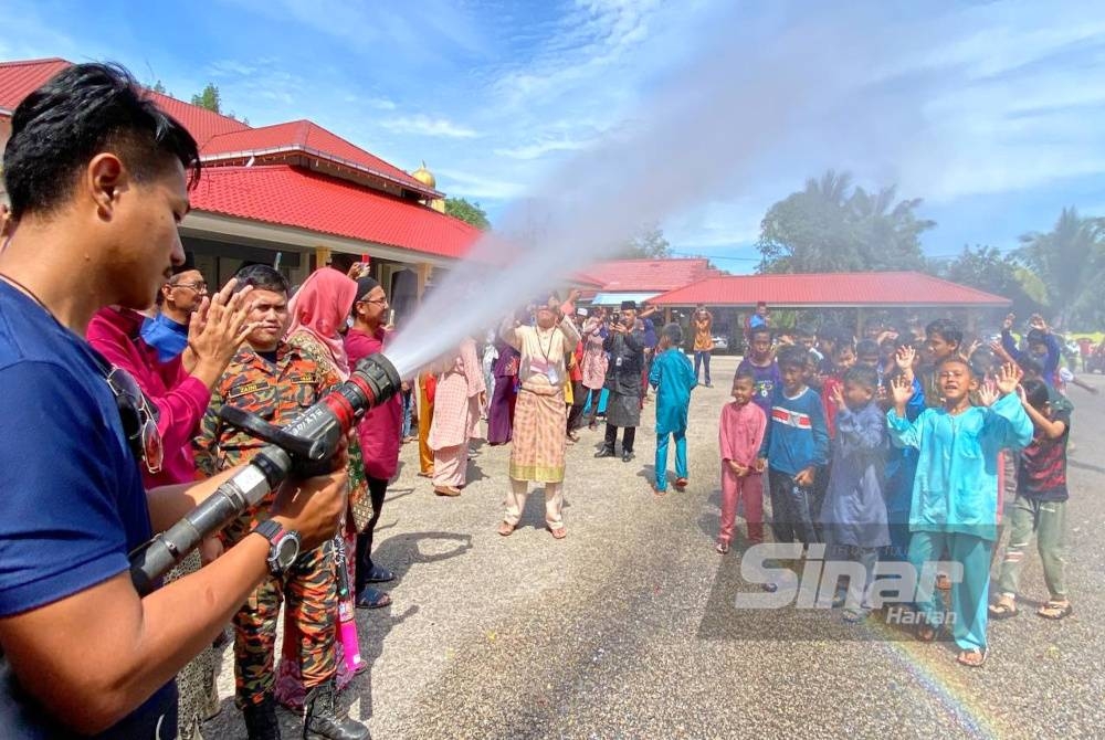Kanak-kanak dimandikan oleh anggota dari Balai Bomba dan Penyelamat Tanah Merah.