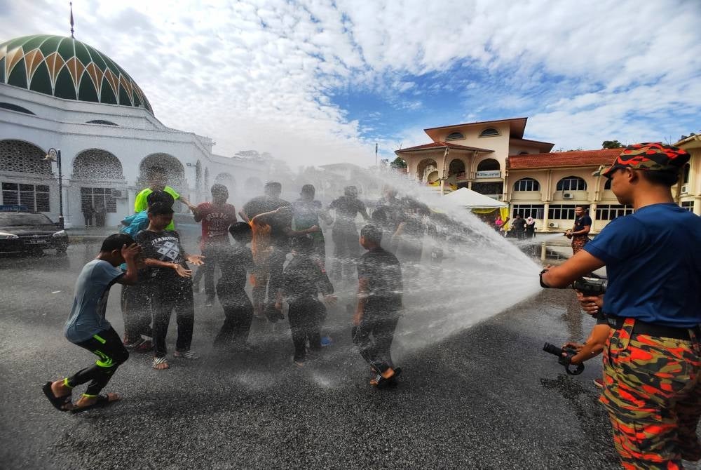 Anggota bomba menyembur air kepada peserta Program Sinar Kedewasaan di Pusat Dakwah Islamiah Paroi pada Ahad.