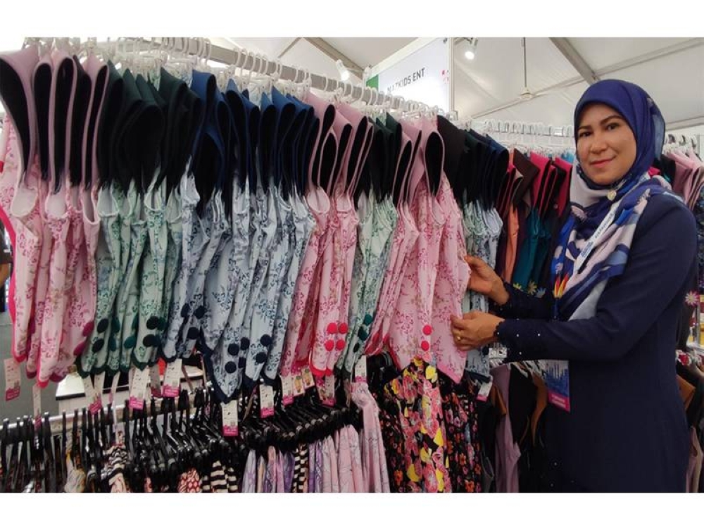 Suzita bersama tudung kanak-kanak yang dihasilkannya.