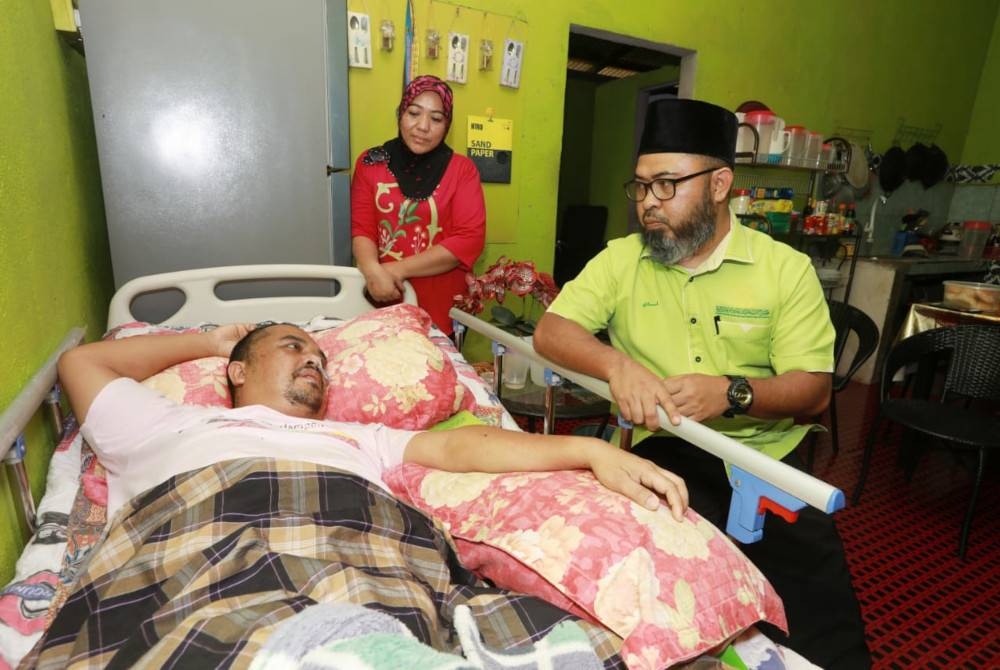 Dr Asmadi ketika melawat dan menyerahkan bantuan kepada Mohd Hairol di Felda Bukit Goh di sini minggu lalu.