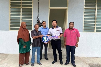 Ahmad Azrin (tengah) menyaksikan penyampaian kunci rumah kepada Mat Rani Deris di Kemaman. Foto Ihsan Maidam