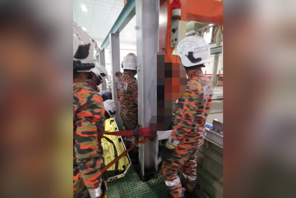 Anggota bomba berusaha mengeluarkan mangsa yang tersepit antara kren dan penghadang besi di sebuah kilang di Taman Perindustrian Tanjung Pelepas pada Selasa. - Foto bomba